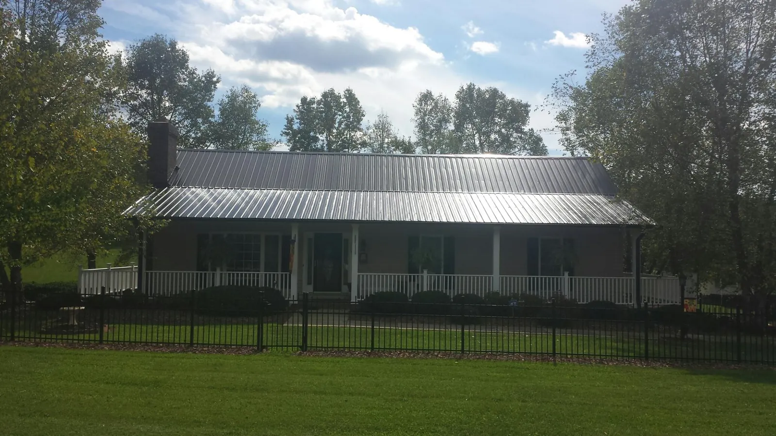 Gray metal roof on a brick ranch with a full width front porch — Gutter Guard Installation work by our crew in Crouse